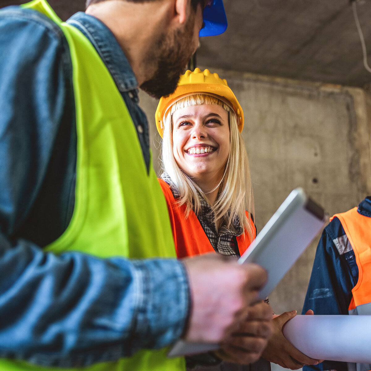 A construction worker is smiling at a colleague