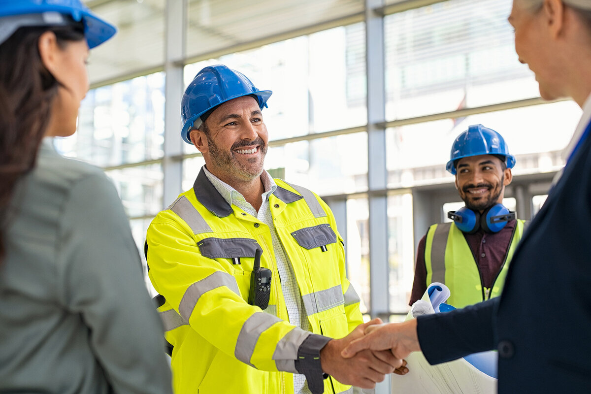 architect and contractor shaking hands at construction site