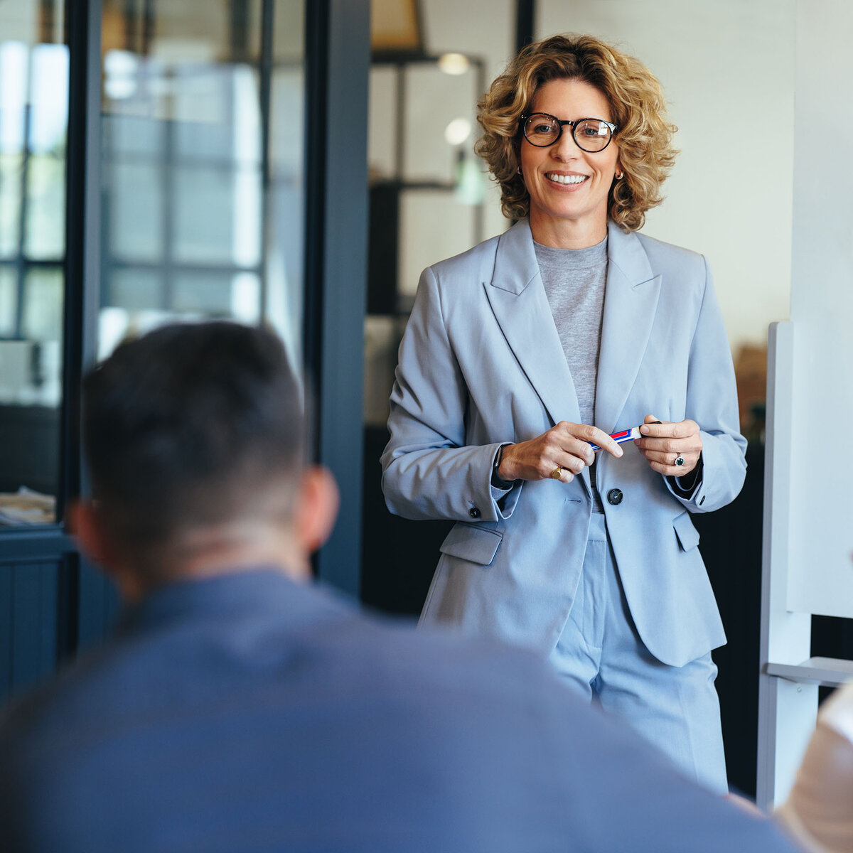 A consultant is standing talking to her client in a bright office