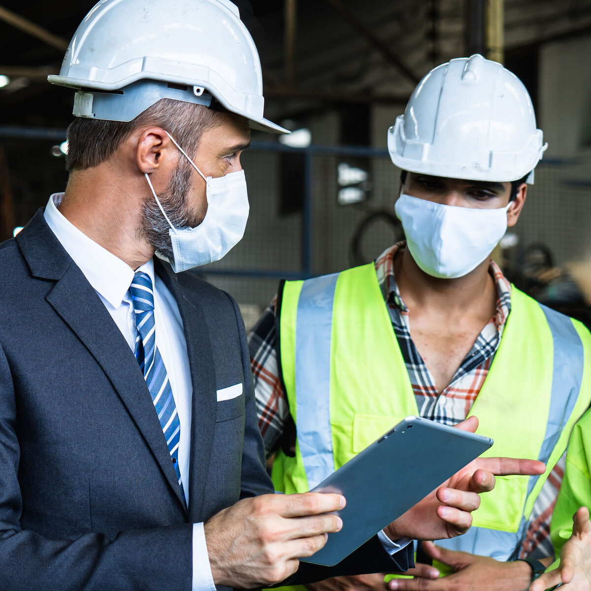 Industrial engineers and businessman in suite and safety helmet wearing mask working in factory