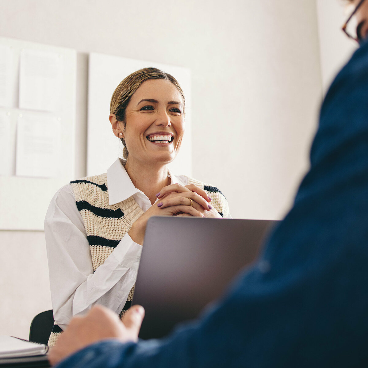 A business woman is smiling and talking to a client in an office