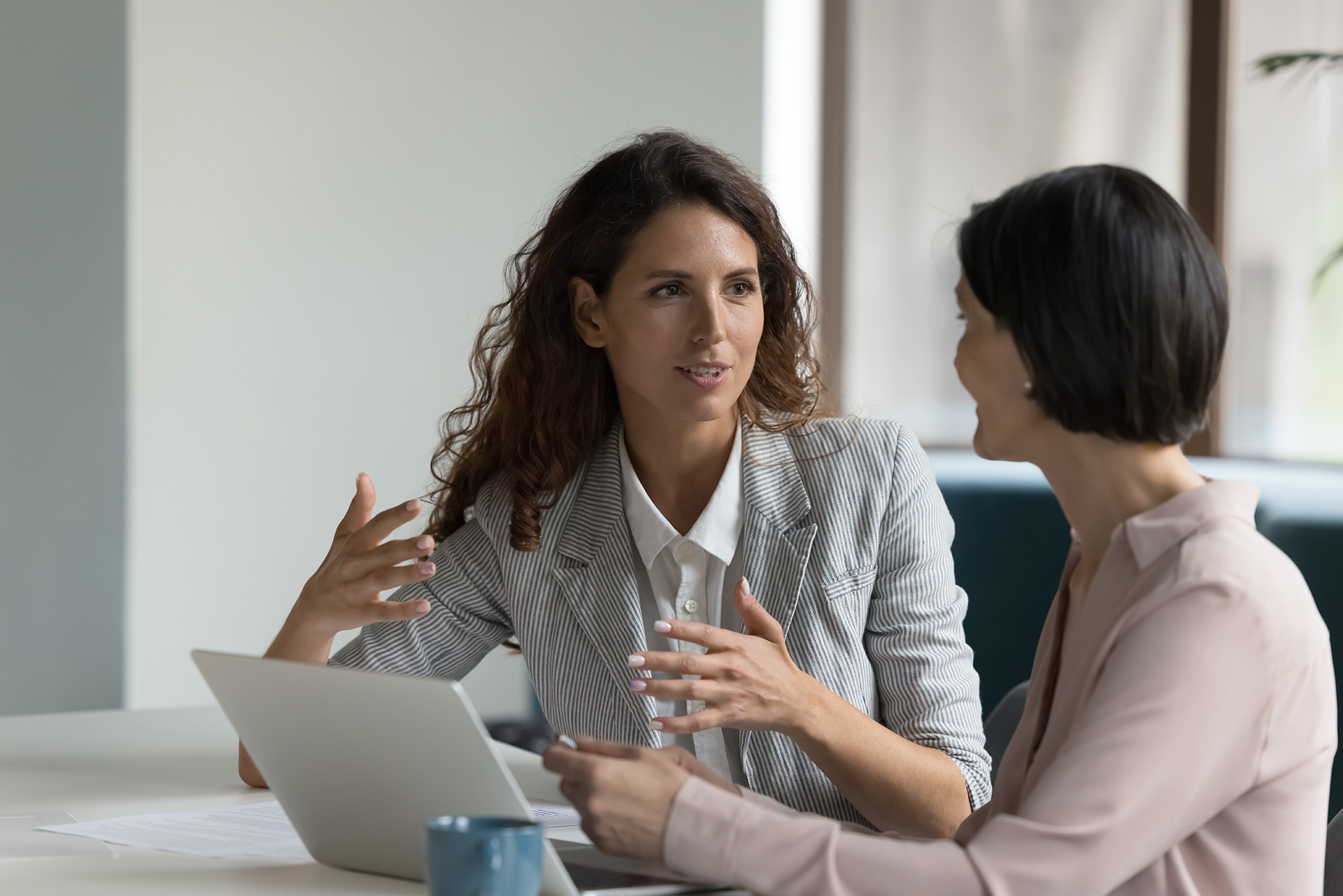 Two business women sit at desk to discuss project details